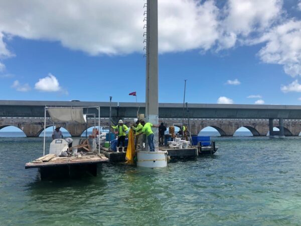 Marine construction project in progress with construction workers installing a transmission pole | Inland Construction & Engineering, Inc. Panama City, Florida providing construction, general contracting, marine construction, design & engineering, diving services, roofing, & bulding rehab.